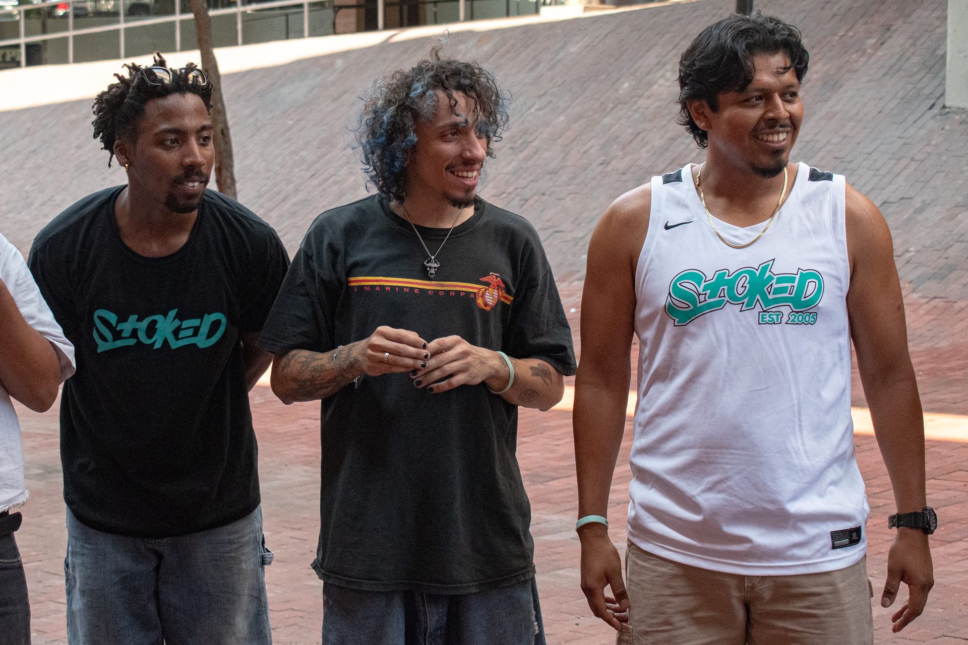 Three STOKED coaches in branded tees standing shoulder to shoulder, mid conversation and laughing.